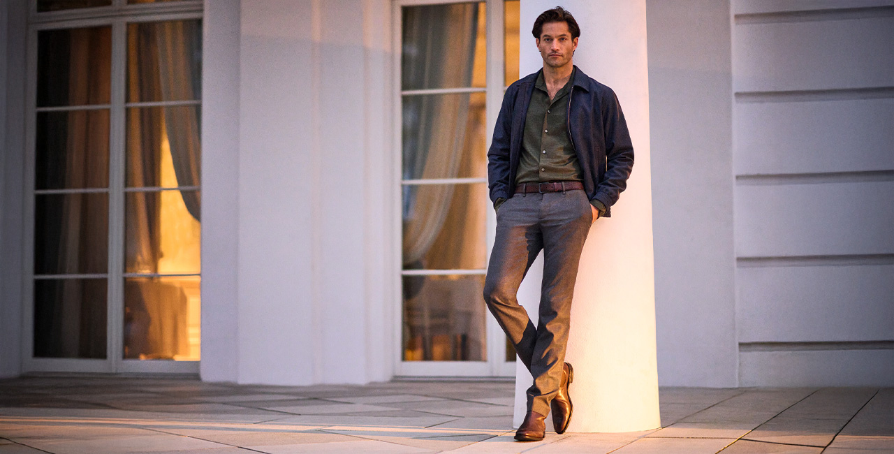 Mann in olivgrünem Hemd, dunkelblauer Jacke und grauer Hose von Alberto, leger an Säule angelehnt