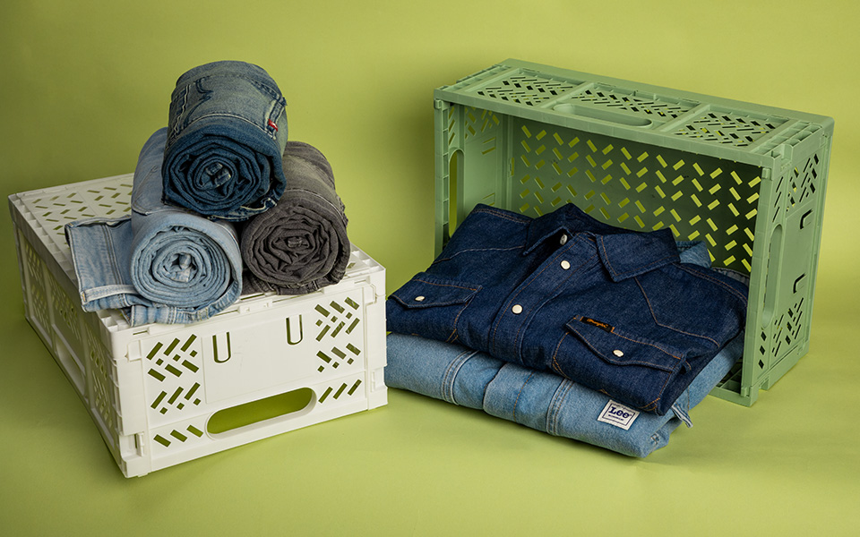 Gefaltetes dunkelblaues Jeanshemd und mehrere Denim-Hosen in Beige-Boxen präsentiert