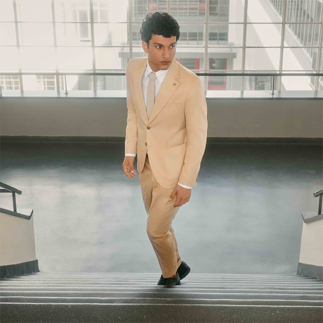 Hellbeiger Anzug mit weißem Hemd und Krawatte, modern geschnitten, getragen im Büro