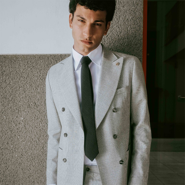 Grauer Zweireiher-Anzug aus Leinen, getragen mit weißem Hemd und schwarzer Krawatte