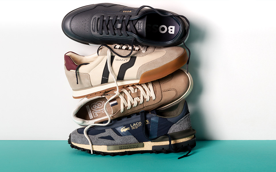 Vier Paar Herrensneaker in verschiedenen Farben und Materialien, gestapelt, Seitenansicht