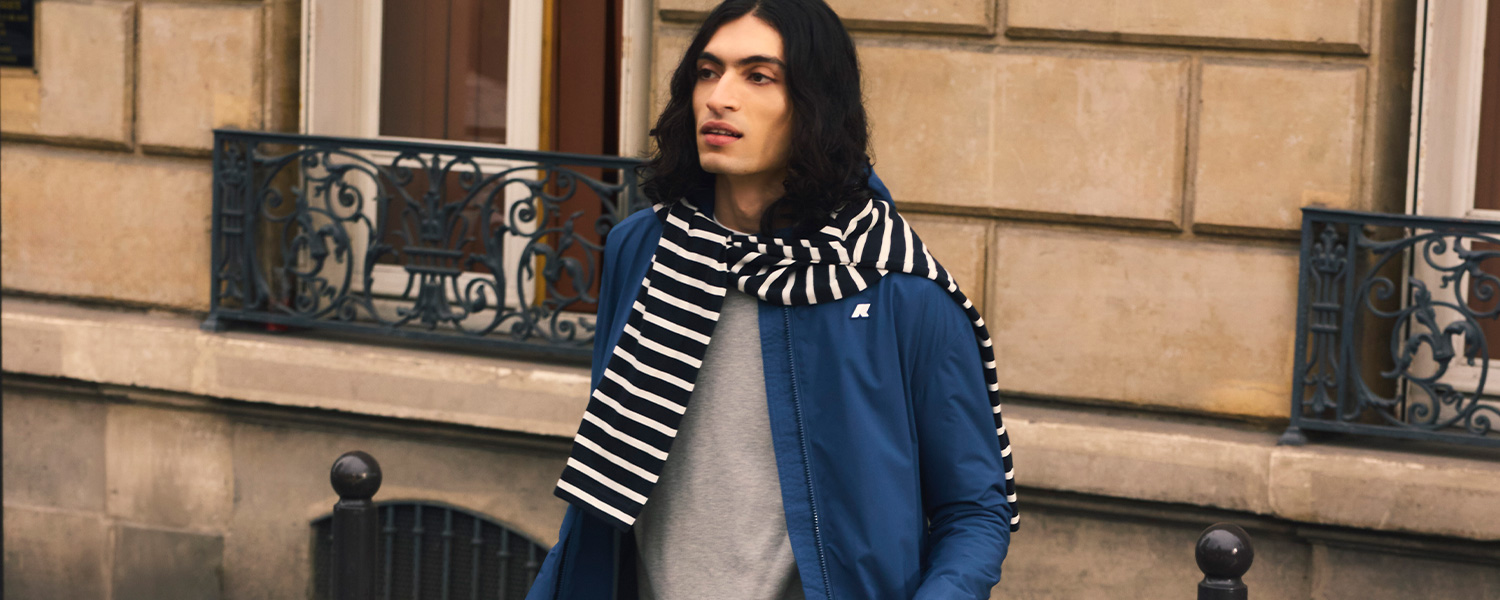 Elegante Herrenjacke in Blau, kombiniert mit einem gestreiften schwarz-weißen Schal auf der Straße getragen