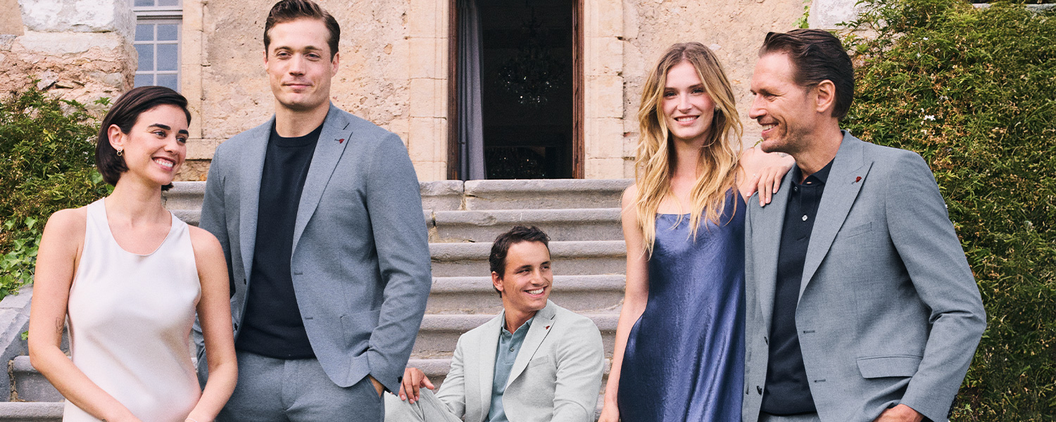 Gruppe in grauen Anzügen und eleganter Freizeitmode vor Steingebäude