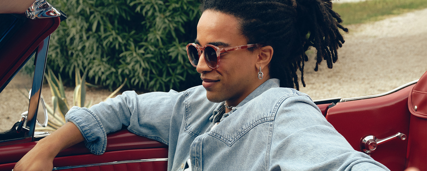 Mann in hellblauer Jeansjacke entspannt im Cabrio sitzend, sommerlich lässig