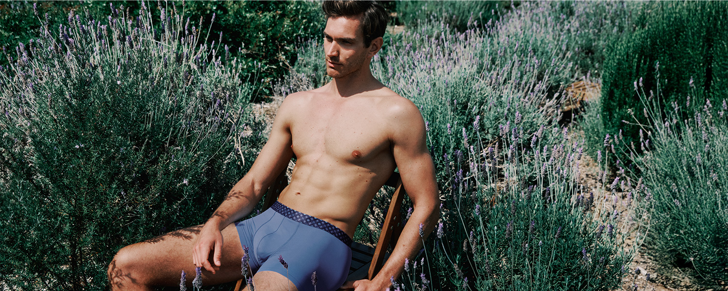 Mann in blauer Unterhose aus Baumwolle, im Freien sitzend