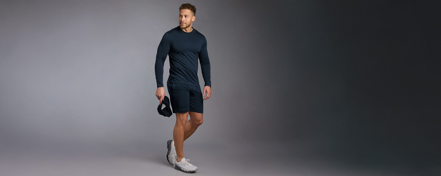 Mann in dunkelblauem Sportset mit Langarmshirt und Shorts, sportlich in Bewegung