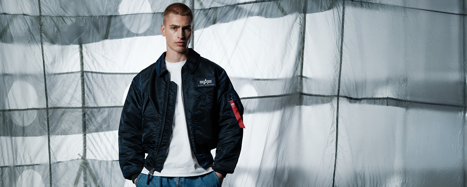 Mann in schwarzer Bomberjacke mit weißem T-Shirt und Jeans, lässiger Look