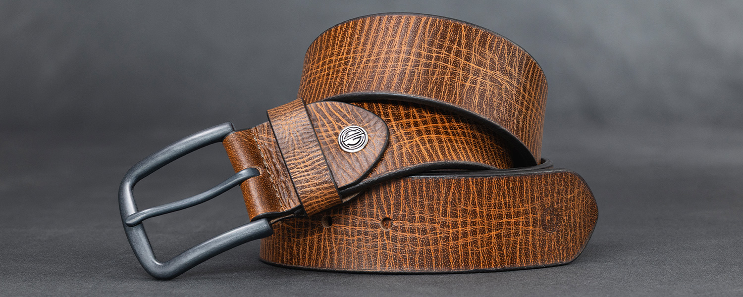 Brauner Ledergürtel mit strukturierter Oberfläche und silberner Schnalle auf grauem Hintergrund