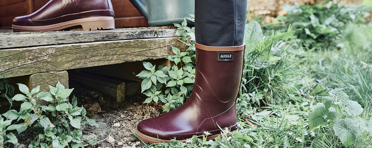 Brauner Gummistiefel aus Lederimitat, getragen im Garten auf Holzstufen