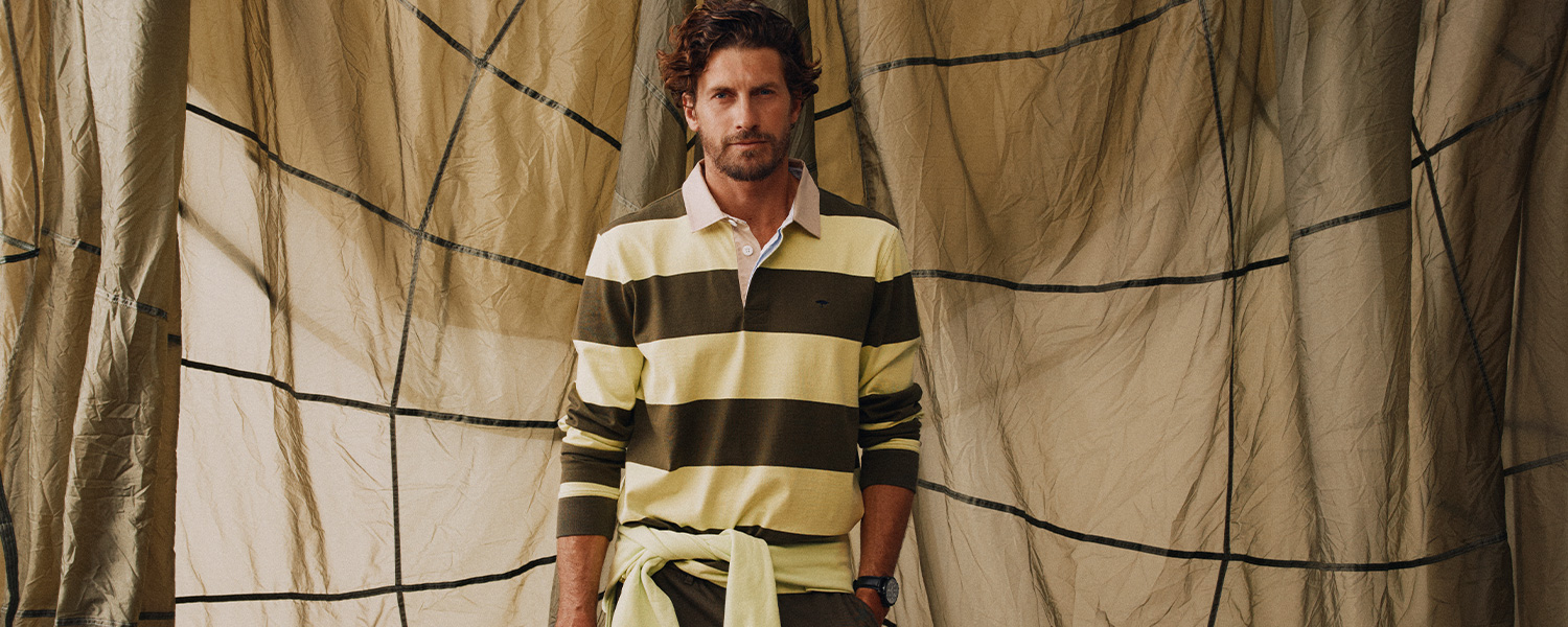Mann in olivgrün-gelb gestreiftem Langarm-Polo aus Baumwolle, lässig präsentiert