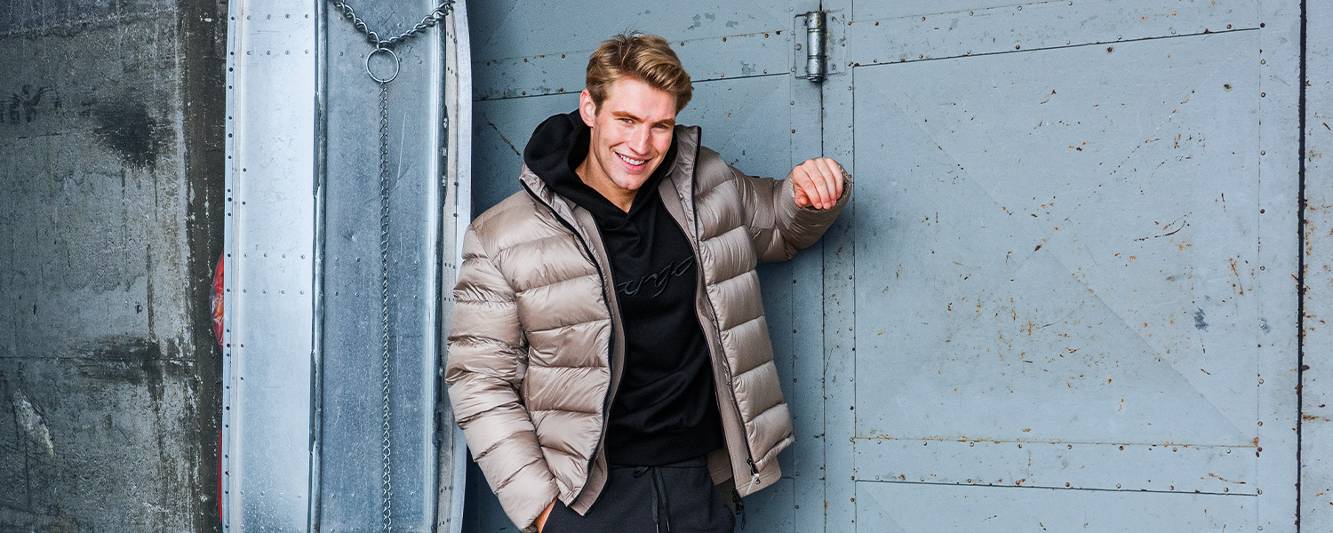 Warme Daunenjacke in Beige, kombiniert mit schwarzem Hoodie und sportlicher Hose – perfekter Begleiter für kalte Tage.