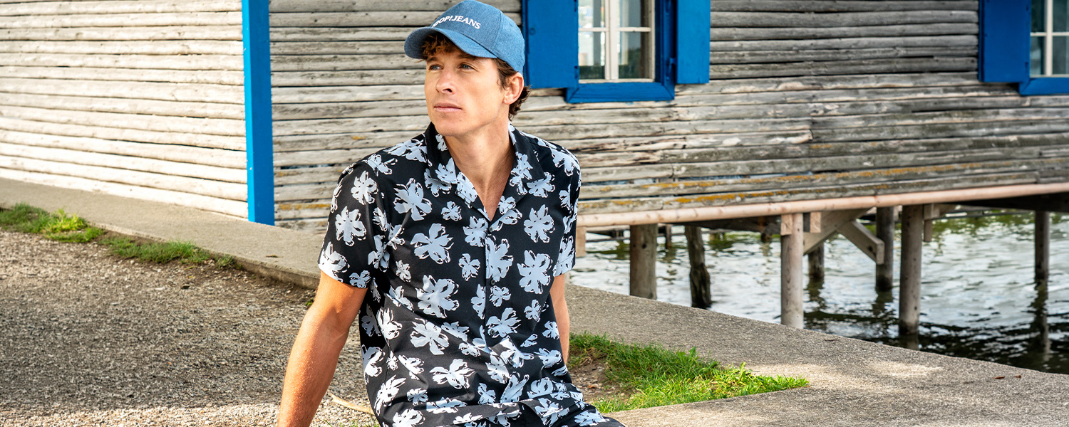 Mann trägt gemustertes Kurzarmhemd mit großen braunen Kreisen in modernem Interieur