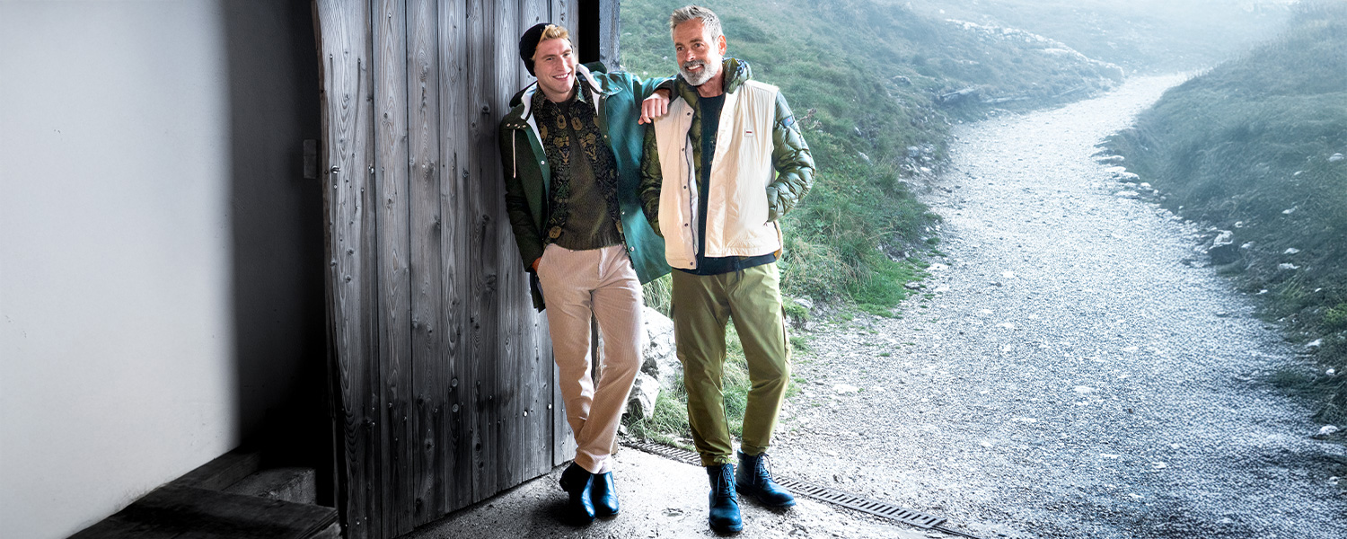 Olivgrüne Cargohose mit Seitentaschen, getragen zu Steppjacke und Weste beim Spaziergang im Gebirge.