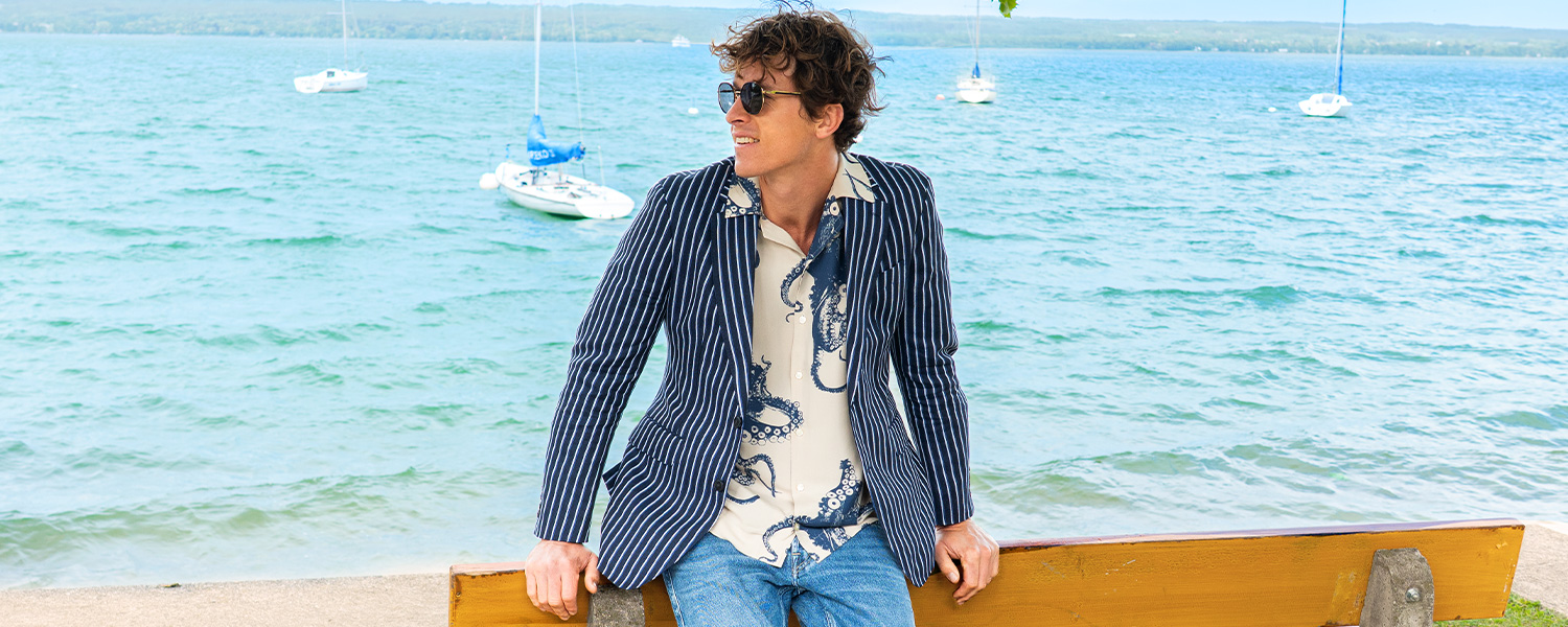 Grünes Freizeithemd aus Cord, kombiniert mit grauer Strickjacke und Basecap im legeren Outdoor-Look.