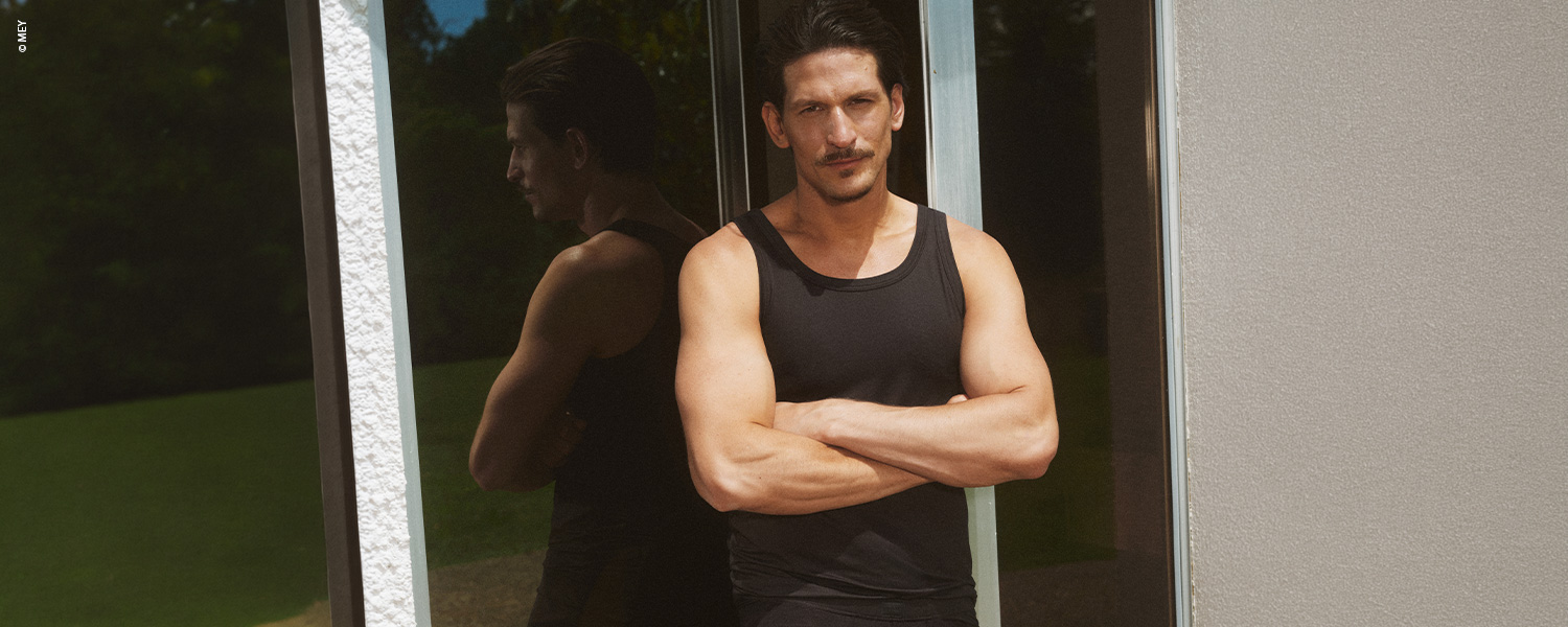 Herr im roten Tanktop vor grauem Hintergrund – ärmellose Herrenunterwäsche.