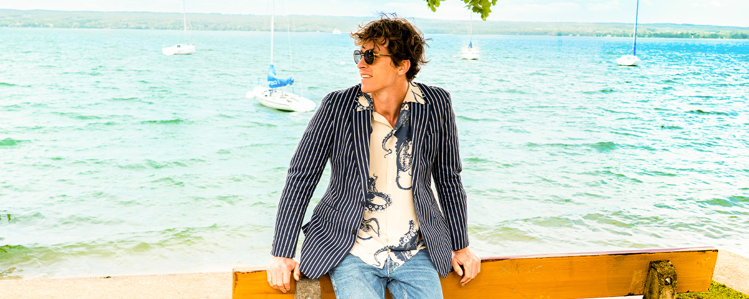 Auf dem Bild trägt ein Mann ein elegantes, weinrotes Sakko mit doppelter Knopfreihe – stilvoll kombiniert für formelle Anlässe.