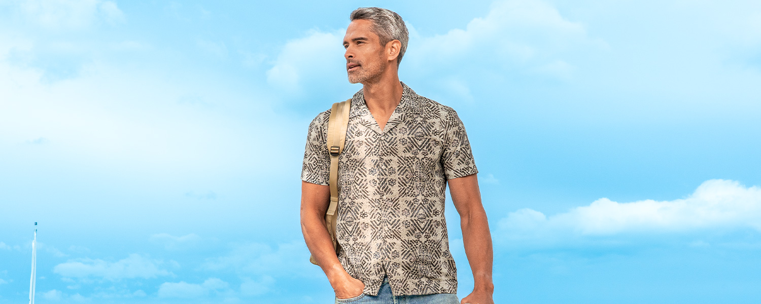 Hellblau-weiß gestreiftes Business-Hemd aus Baumwolle, getragen unter grünem Anzug mit Hut im Outdoor-Setting.