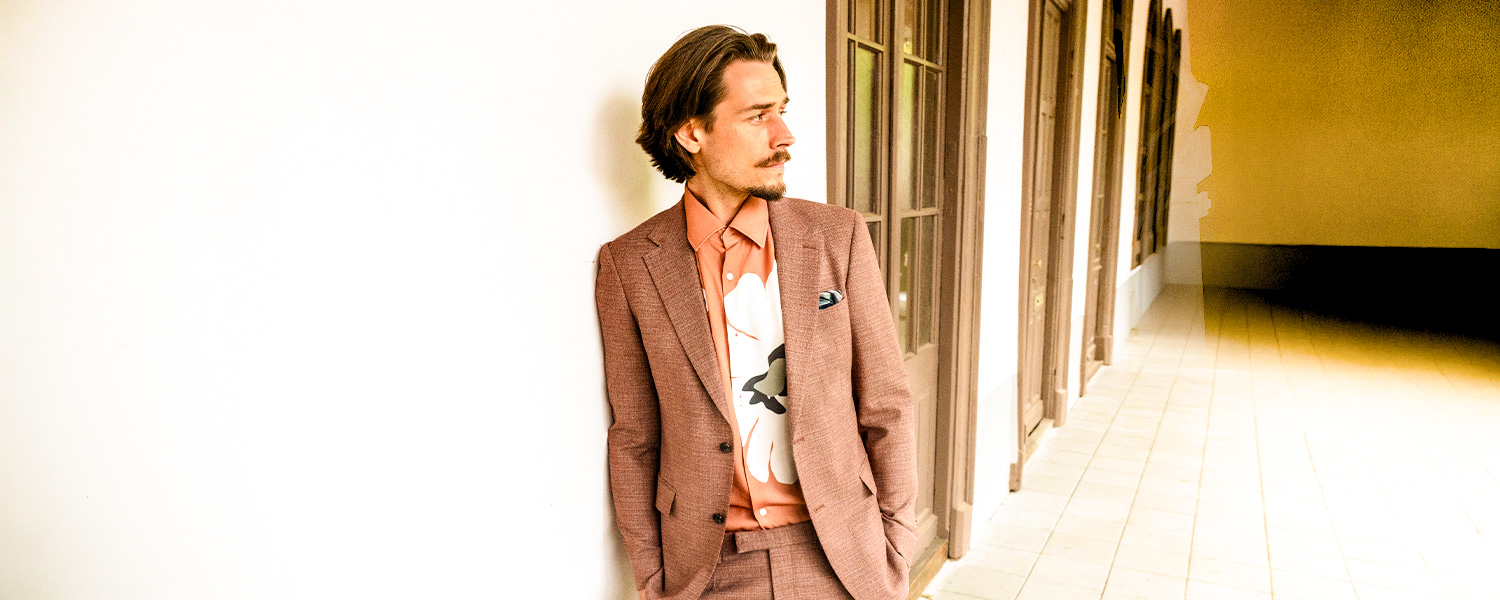 Auf dem Bild trägt ein Mann ein elegantes, weinrotes Sakko mit doppelter Knopfreihe – stilvoll kombiniert für formelle Anlässe.