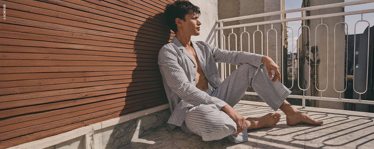 Ein Mann trägt einen karierten Pyjama mit langem Oberteil und langer Hose.