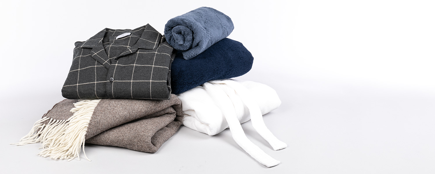 Grauer Pyjama mit Karomuster aus Baumwolle, gefaltet auf Deckenset in Blau, Weiß und Grau