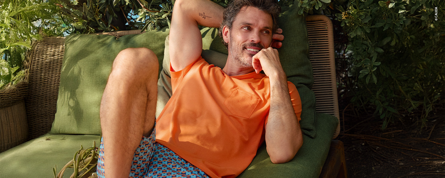 Ein Mann trägt einen kurzärmligen Pyjama mit gemusterten Shorts und passendem T-Shirt.