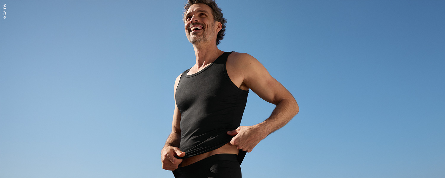 Herr im roten Tanktop vor grauem Hintergrund – ärmellose Herrenunterwäsche.