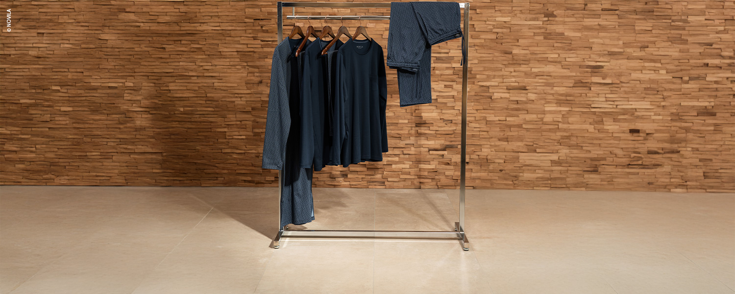 Ein Kleiderständer mit dunkelblauen Nachthemden und Schlafanzügen, ordentlich aufgehängt.