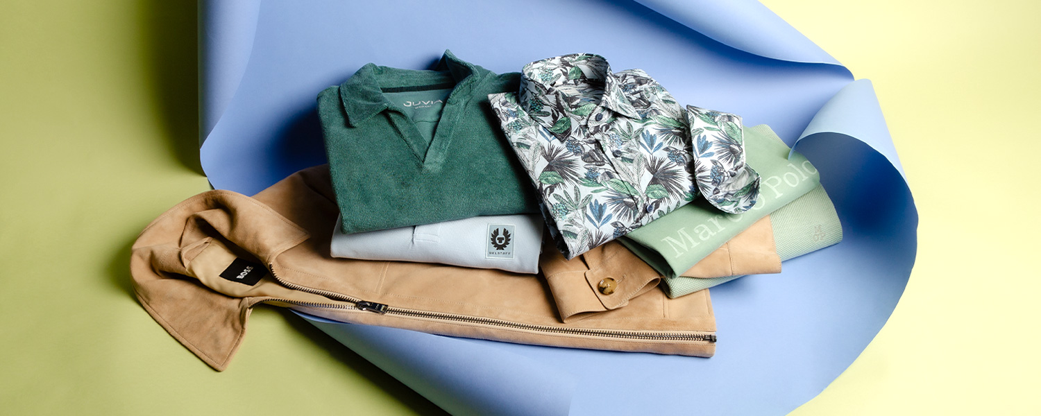 Grünes Poloshirt und bedrucktes Freizeithemd mit beigem Wildlederjacke elegant gestapelt.