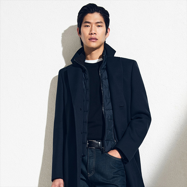 Herrenmantel in Schwarz, über gestepptem Pullover, elegante Präsentation