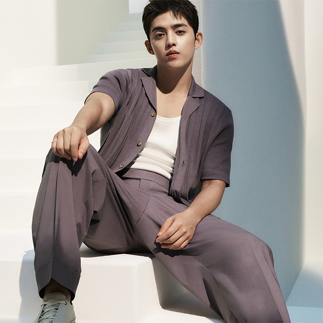 Mann in grauem Sommeranzug mit weißem T-Shirt, entspannt sitzend auf Treppe