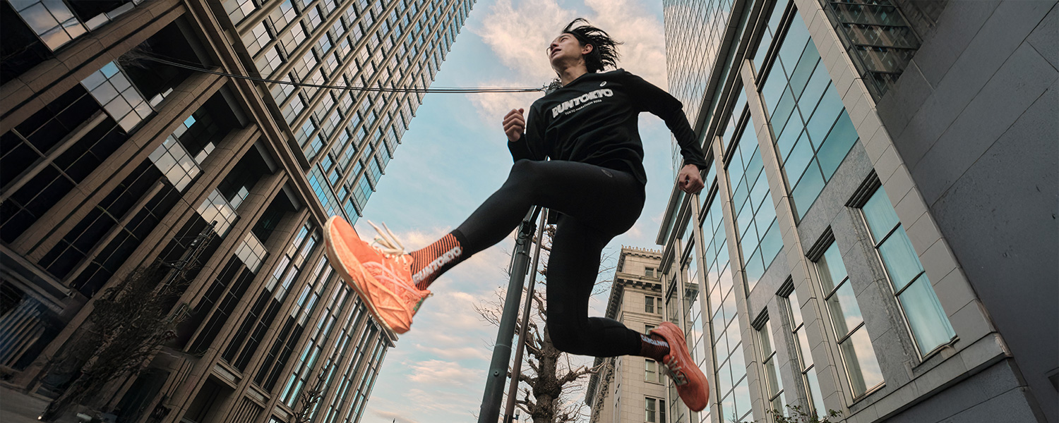 Jogger in schwarzen Leggings und Pullover, mit orangefarbenen Laufschuhen, läuft in der Stadt