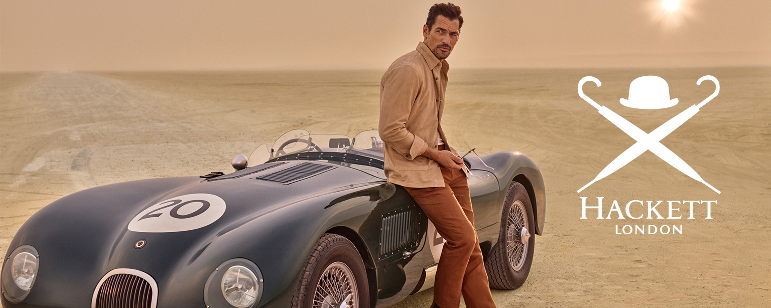 Beiger Blouson und braune Hose, lässig getragen, neben einem klassischen Auto in der Wüste