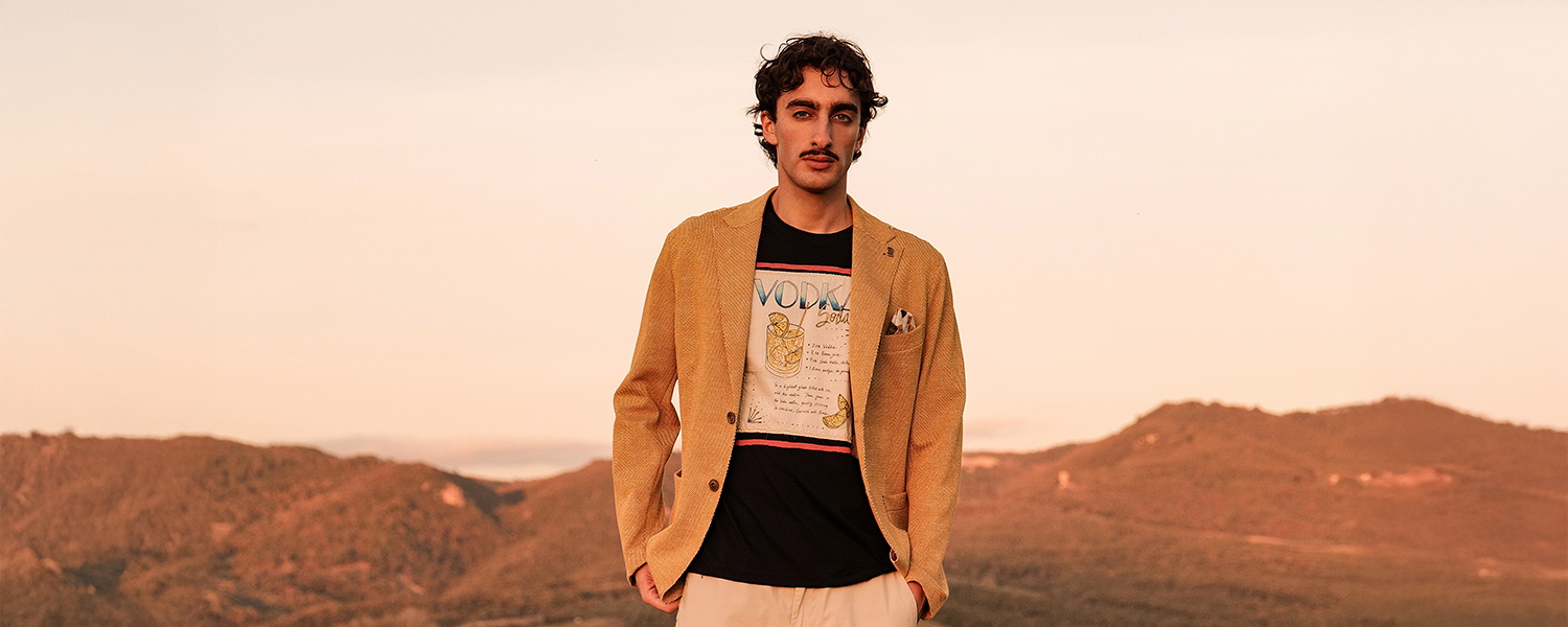 Beiger Leinen-Blazer über schwarzem Print-T-Shirt, leger getragen in landschaftlicher Umgebung