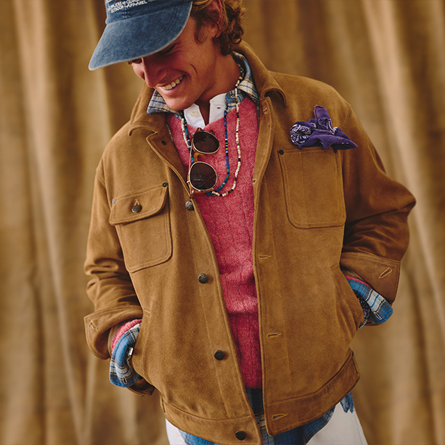 Hellbraune Wildlederjacke über rotem Pullover, lässig mit Jeanshemd und Mütze kombiniert