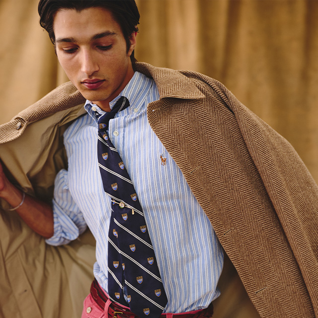 Blau-weiß gestreiftes Business-Hemd mit gestreifter Krawatte, brauner Mantel lässig über die Schulter gelegt