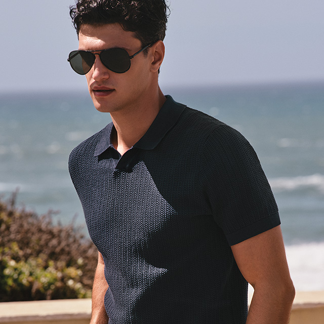 Mann in dunkelblauem Poloshirt aus Strukturstoff am Meer