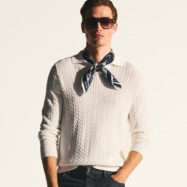 Eleganter weißer Strickpullover mit Zickzackmuster, getragen mit dunkler Jeans