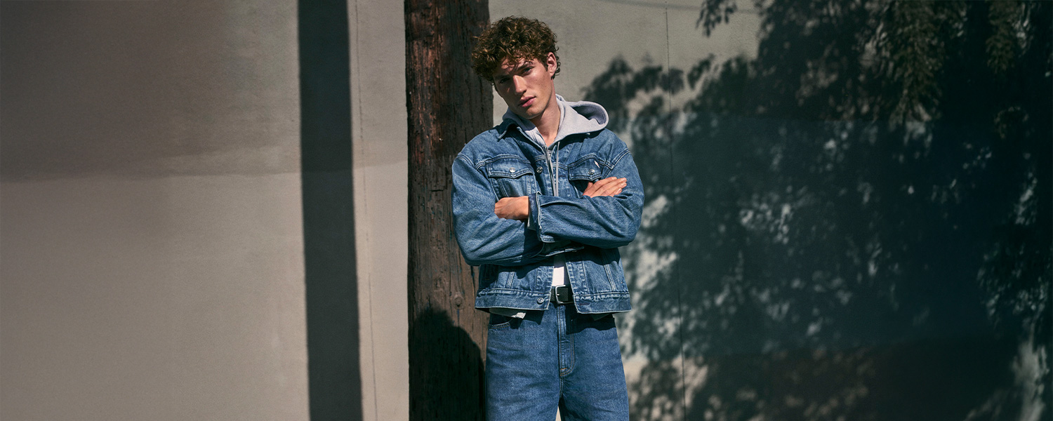 Jeansjacke in Blau mit grauem Kapuzenpulli, lässig getragen