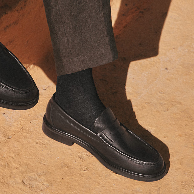 Schwarze Lederloafer mit dunkler Socke, kombiniert mit grauer Anzughose