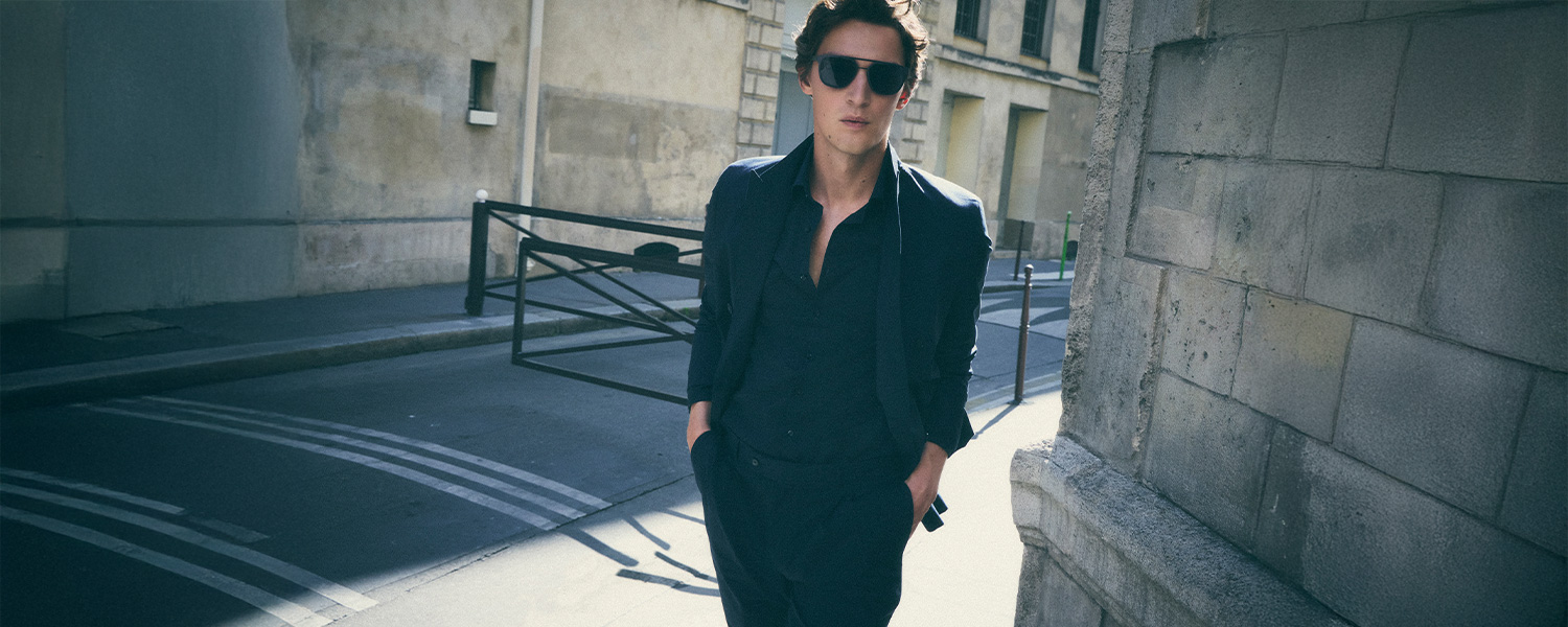 Mann in dunkelblauem Anzug mit freiem Hemdkragen auf urbaner Straße