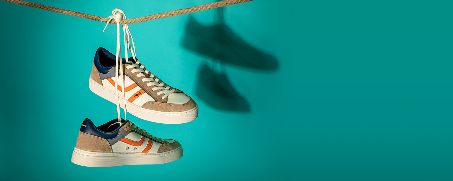 Elegante Sneaker in Beige-Blau mit orangefarbenen Akzenten, aus Wildleder und Textil, hängend präsentiert