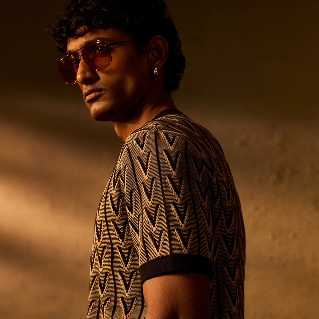 Herr in beige-schwarz gemustertem Strickpullover mit geometrischem Design, elegant präsentiert