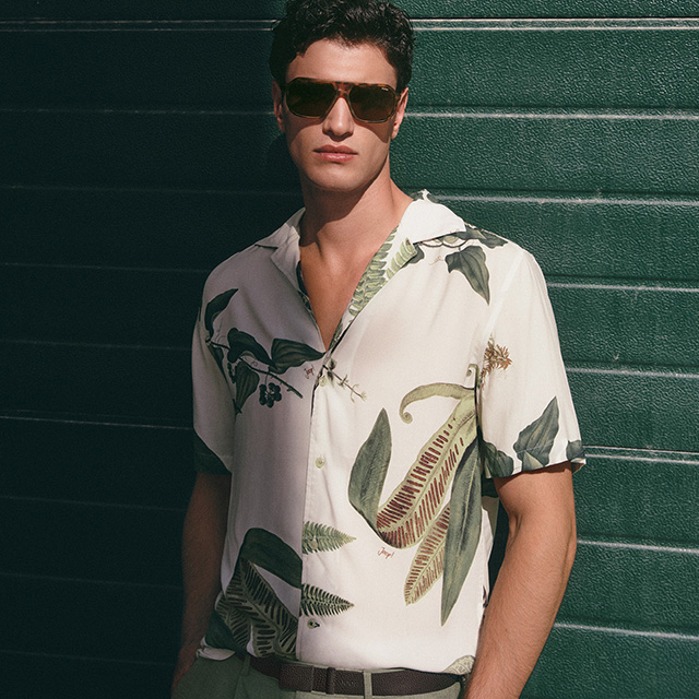 Herr in weißem Kurzarmhemd mit botanischem Muster, Freizeitstil im Freien