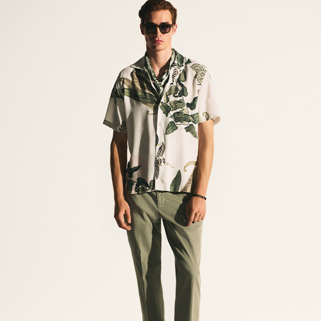 Mann in floralem Kurzarmhemd mit grüner Hose, lässig getragen