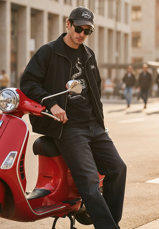 Schwarze Jacke und Jeans, lässig getragen von Mann auf rotem Motorroller in der Stadt