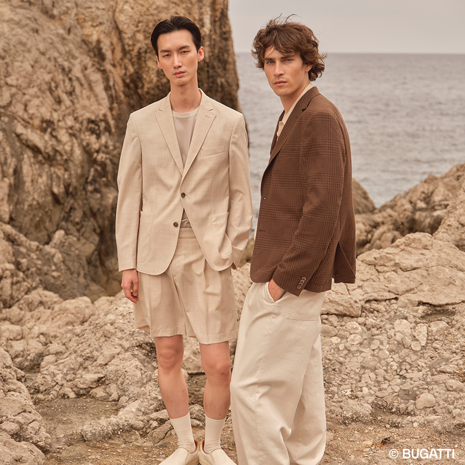 Herren in hellbeigem und braunem Sakko aus Leinen am Strand stehend