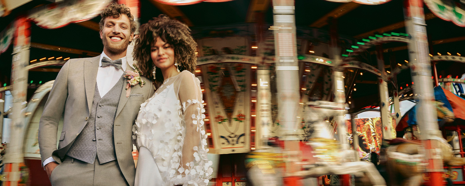Grau melierter Anzug mit weißem Hemd und Krawatte, eleganter Look, getragen von Mann vor Karussell