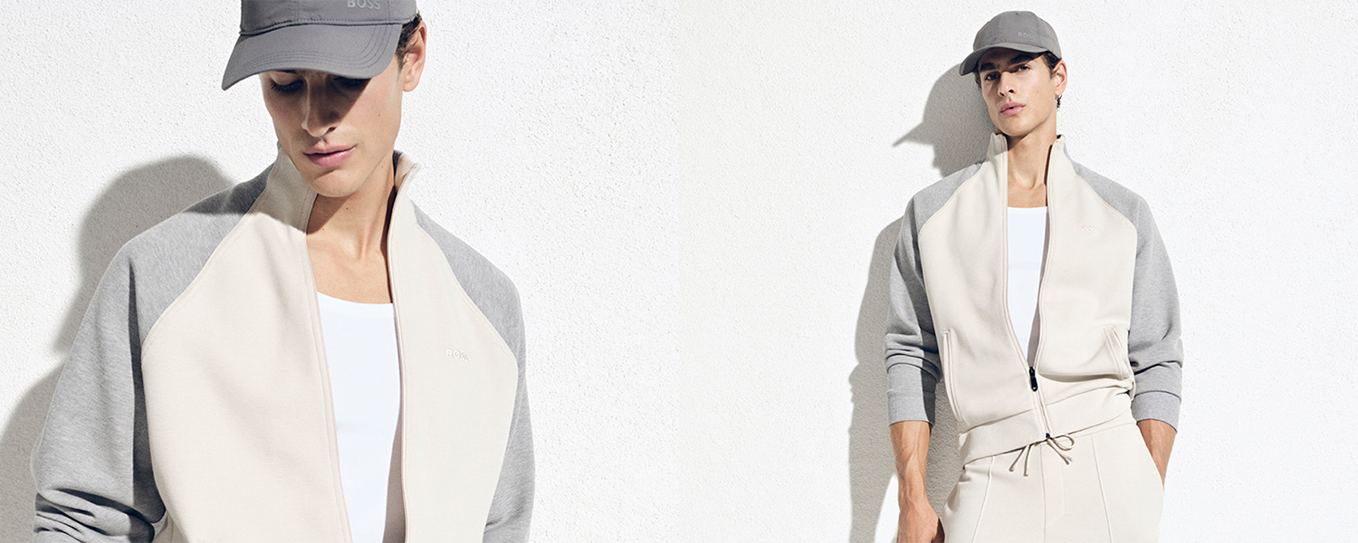 Mann in cremefarbener Sweatjacke mit grauen Ärmeln und Basecap, modern lässig getragen