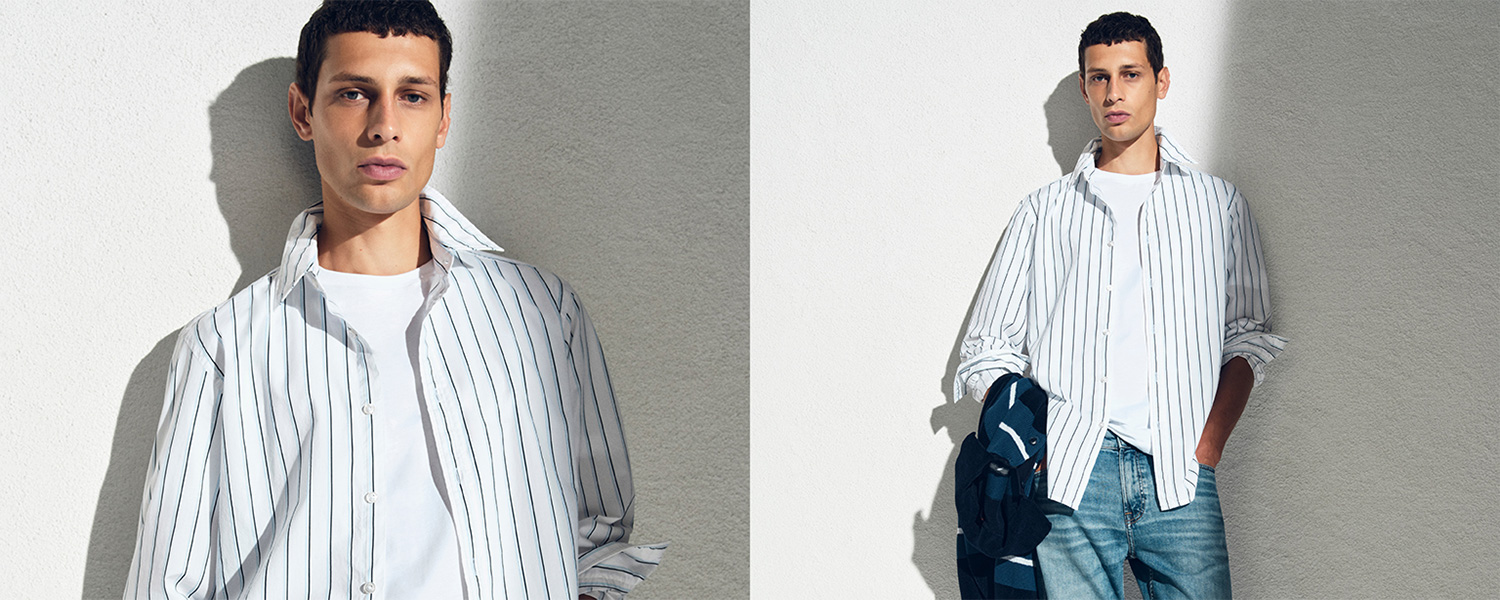 Gestreiftes Herrenhemd in Weiß-Blau, über weißem T-Shirt getragen, legerer Look