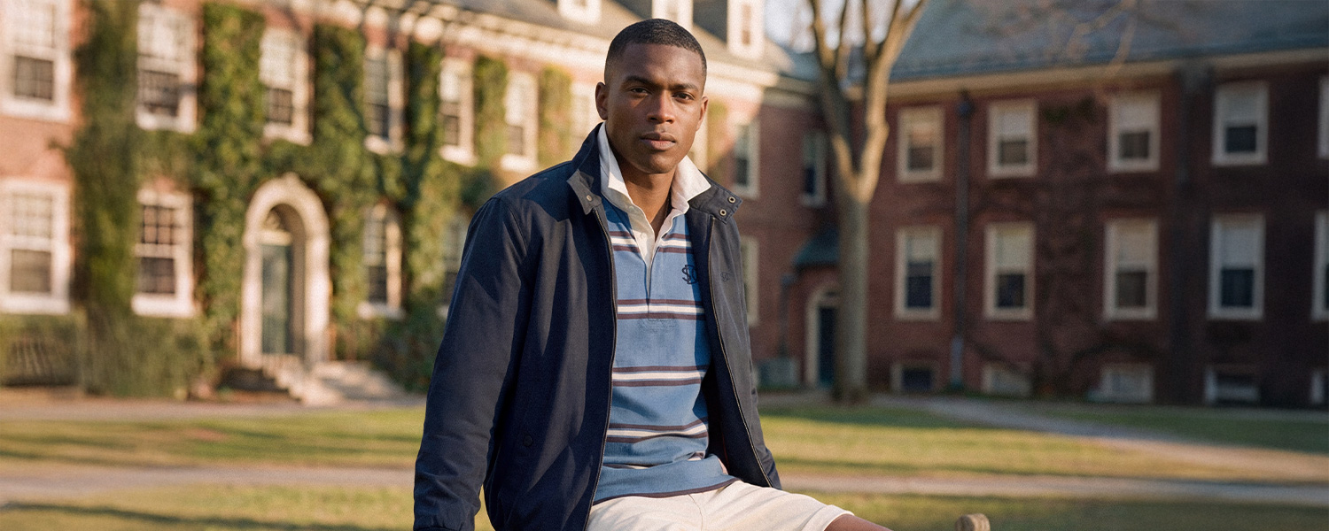 Mann in dunkelblauer Jacke und gestreiftem Poloshirt auf Campus